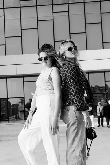 Two stylish women posing back to back outdoors