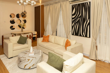 Modern living room with white furniture and zebra print artwork.